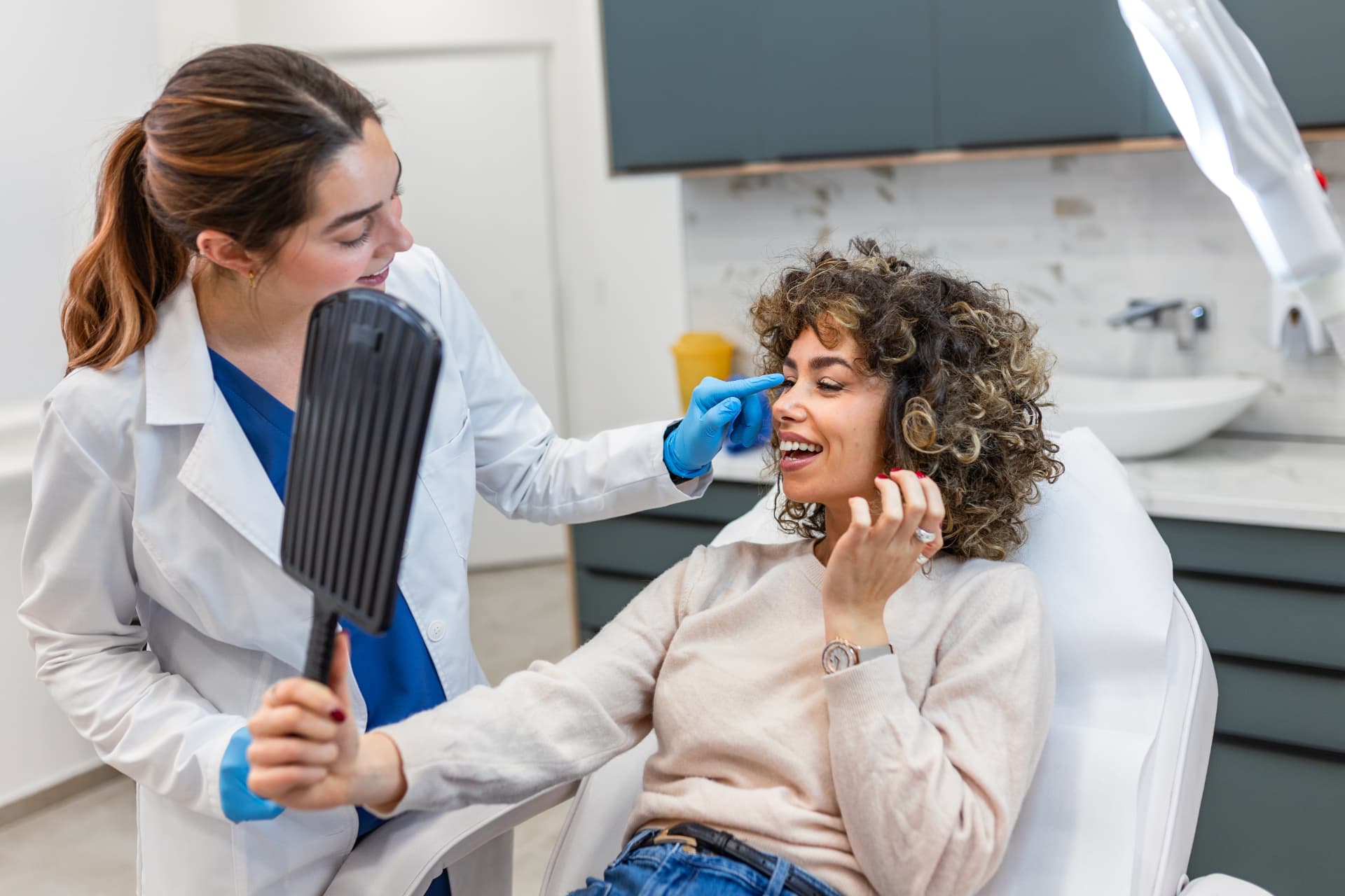 Profissional de saúde apresentando o resultado do tratamento a uma paciente sorridente em consultório